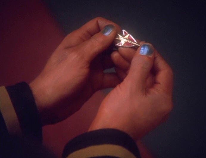 Close-up of Nog's hands as he holds the Red Squadron pin handed to him in 'Valiant'