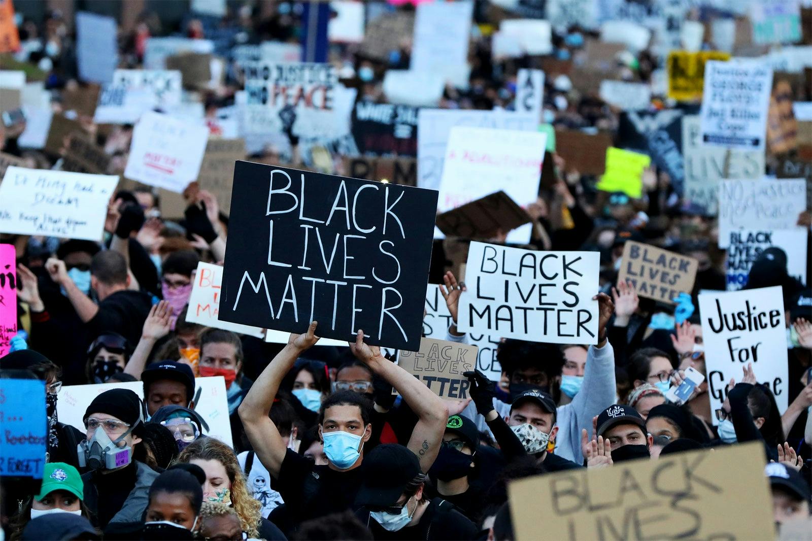 People carry Black Lives Matter signs at a protest against police brutality in Boston, Massachusetts, in May 2020, after the death of George Floyd. Floyd, a Black man, died while being arrested in Minneapolis, Minnesota, with a white police officer kneeling on Floyd's neck for several minutes.