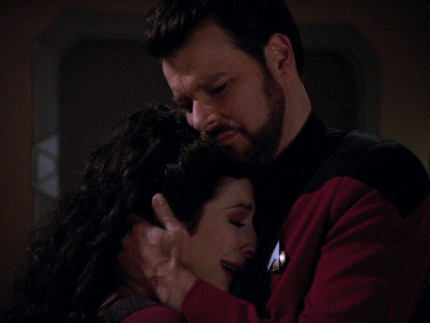 Riker embraces and comforts Deanna Troi as she grieves the loss of her abilities