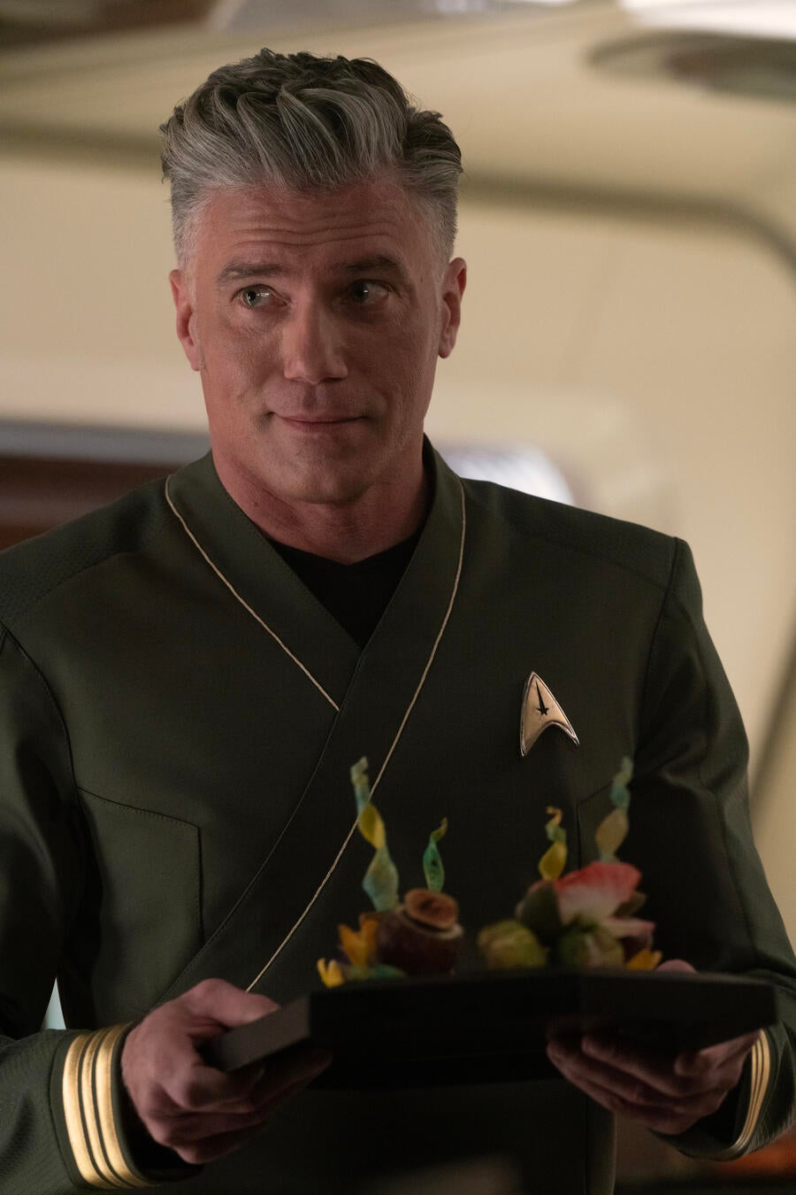 Captain Pike, in his green formal command shirt, carries a tray of crudite in &#x27;Charades&#x27;