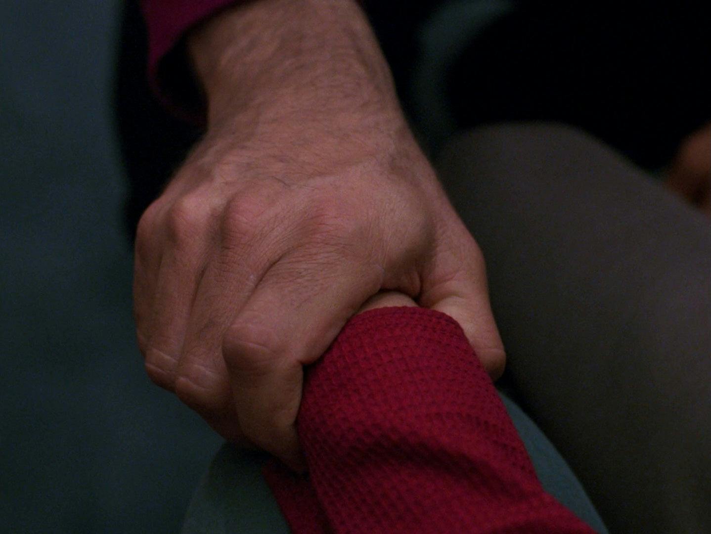 Picard reaches out and holds Jeremy Aster's hand in The Next Generation's The Bonding