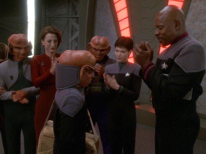 Nog returns home to Deep Space 9 and is welcomed by Rom, Kira, Quark, Ezri Dax, and Sisko in 'It's Only A Paper Moon'