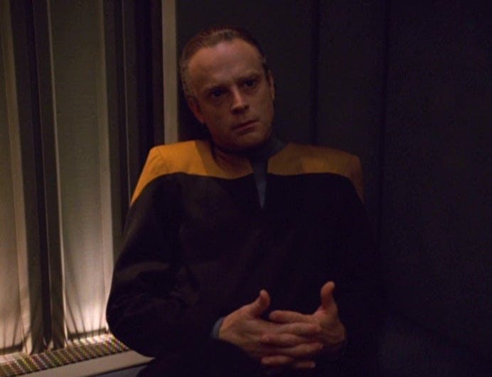 Suder sits in the Brig with his hands interlaced on Star Trek: Voyager