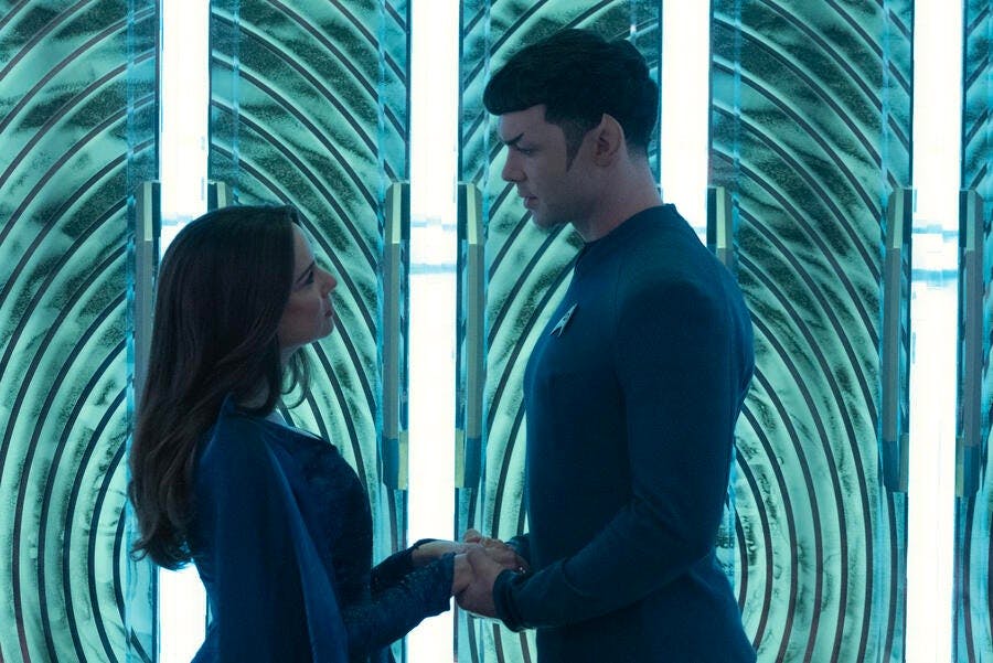 Amanda Grayson and Spock stand on the transporter pad holding hands and each other's gaze in 'Charades'