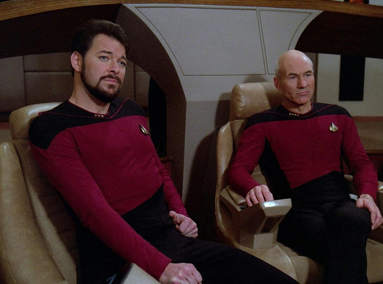 On the bridge of the Enterprise, Riker sits next to Picard who's in the center seat as they both look ahead at the viewscreen in 'The Icarus Factor'