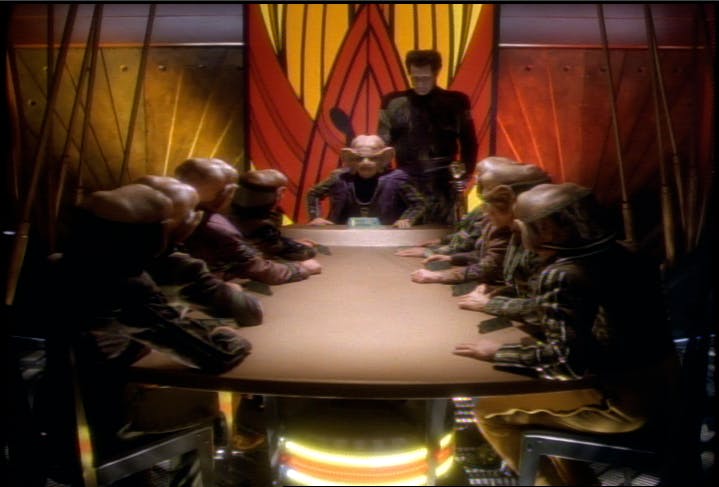 Zek sits at the head of a conference table in 'The Nagus'