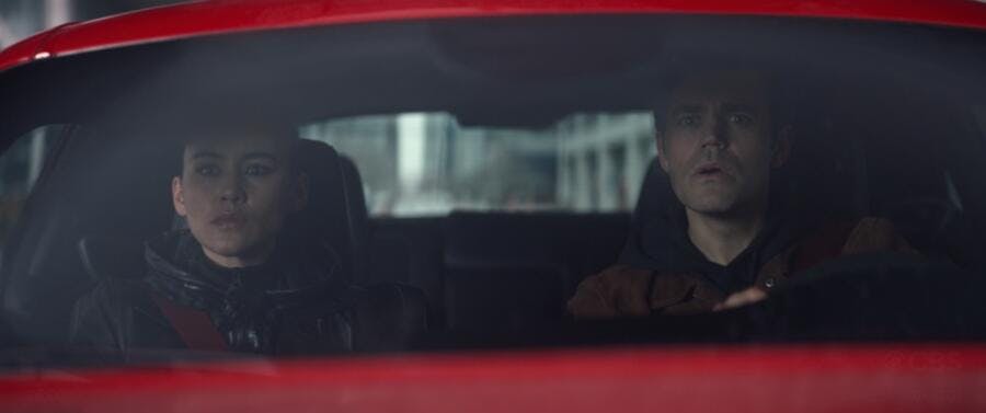 La'An and James Kirk driving in a red car concerned at what they see ahead in 'Tomorrow and Tomorrow and Tomorrow'