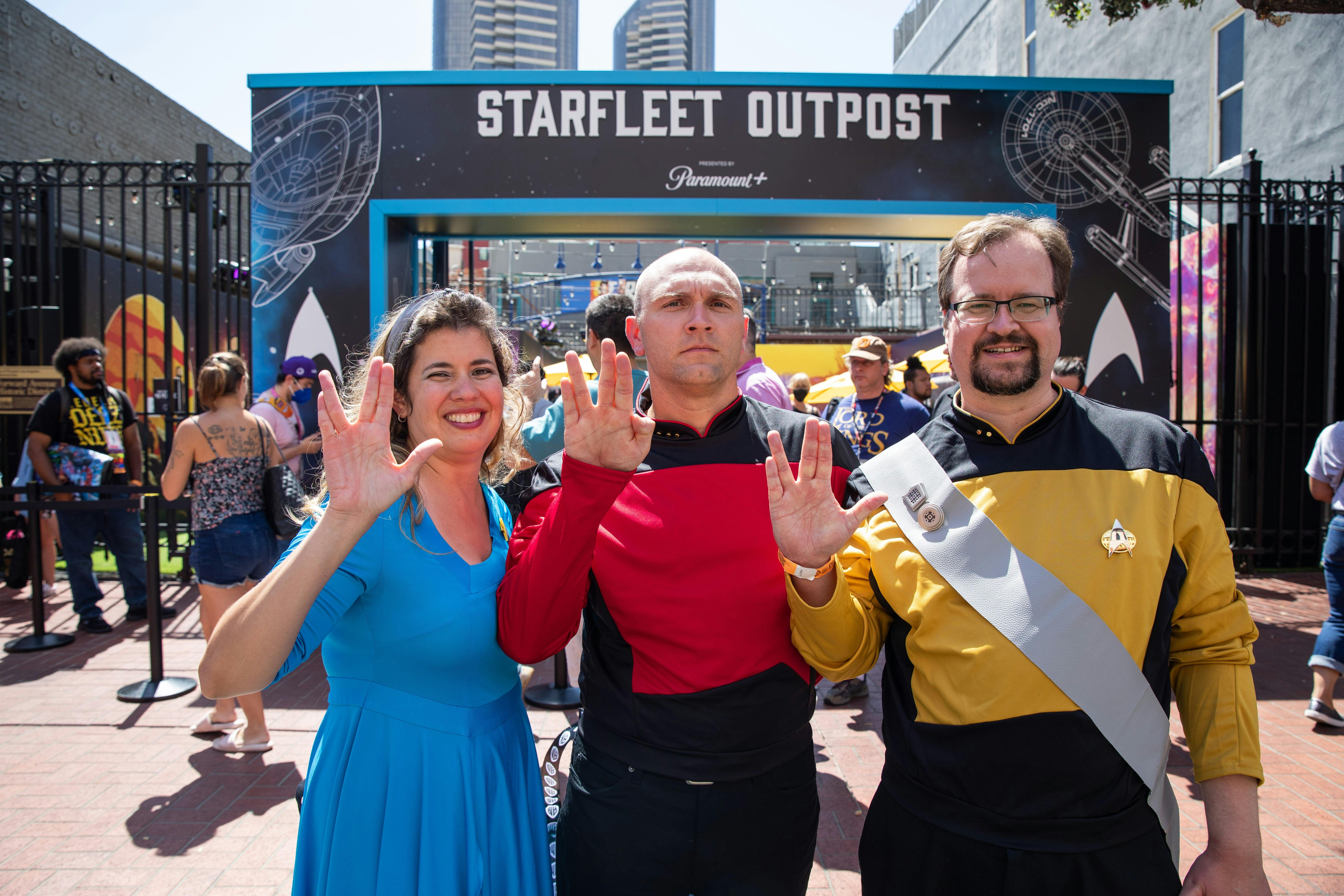 Three fans, in uniform, pose outside of the Starfleet Outpost.
