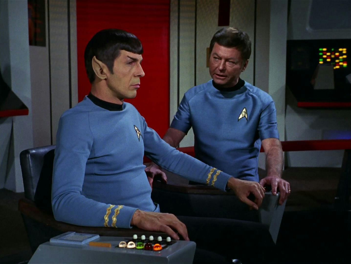 A McCoy faces a stoic and seated Spock who looks out directly in front of him on the bridge of the Enterprise in 'The Tholian Web'