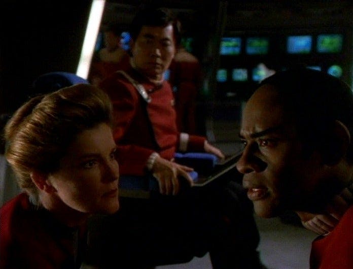 Janeway and Tuvok confer as Captain Sulu watches them.
