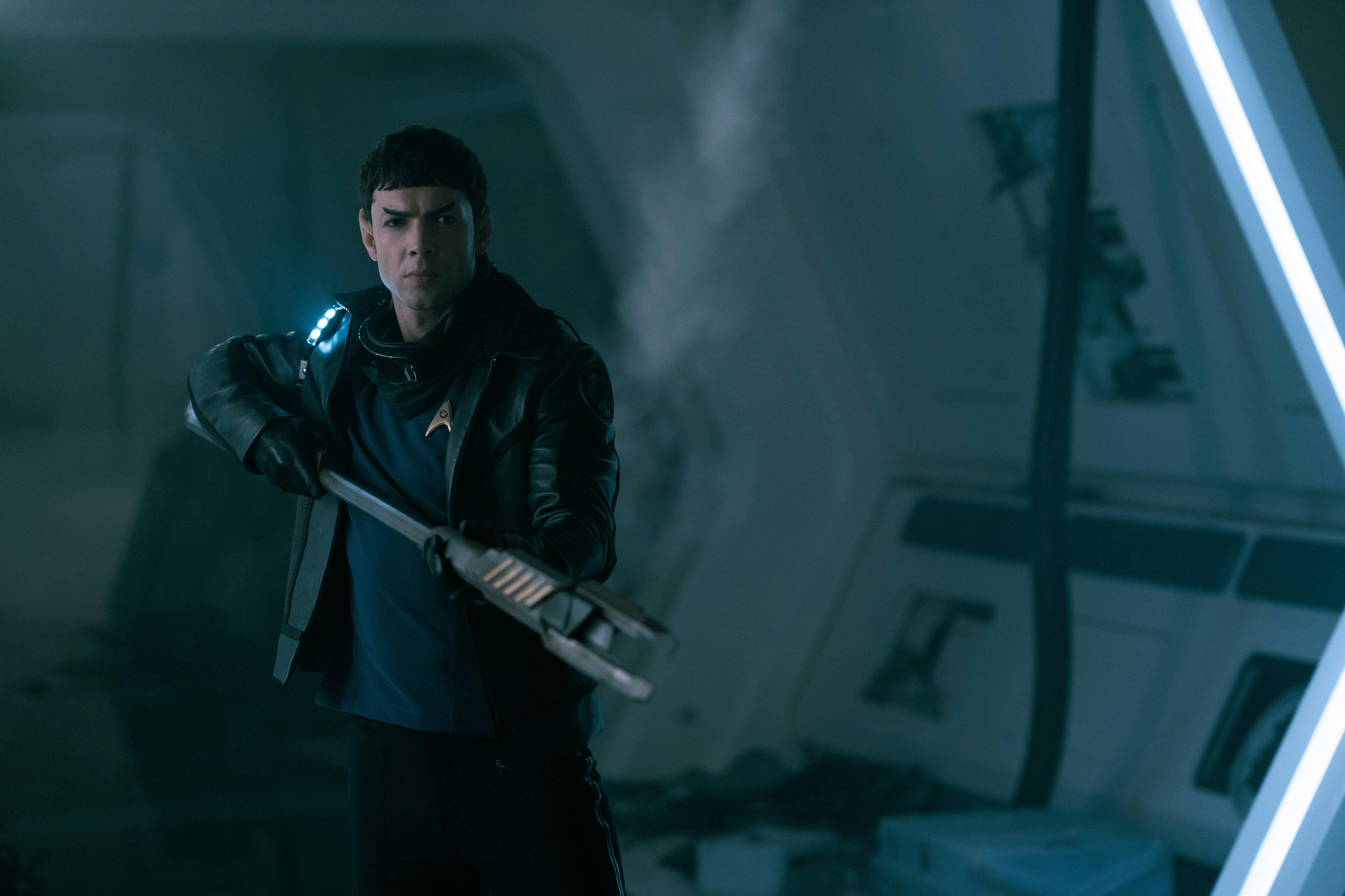 Spock (Ethan Peck) holds a weapon and stands at the ready.