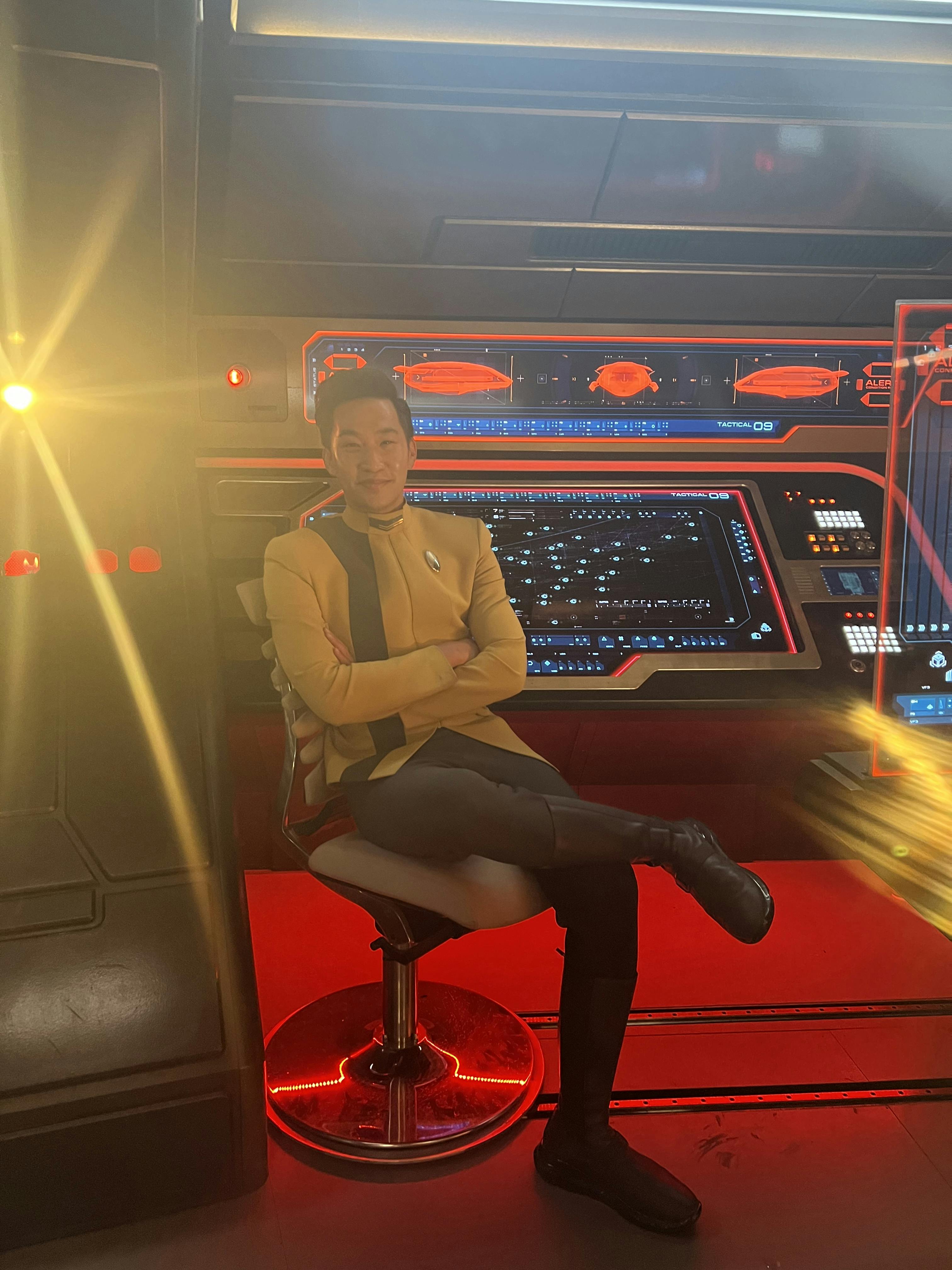 Behind-the-scenes photo of Patrick Kwok-Choon as Gen Rhys at his station on the U.S.S. Discovery