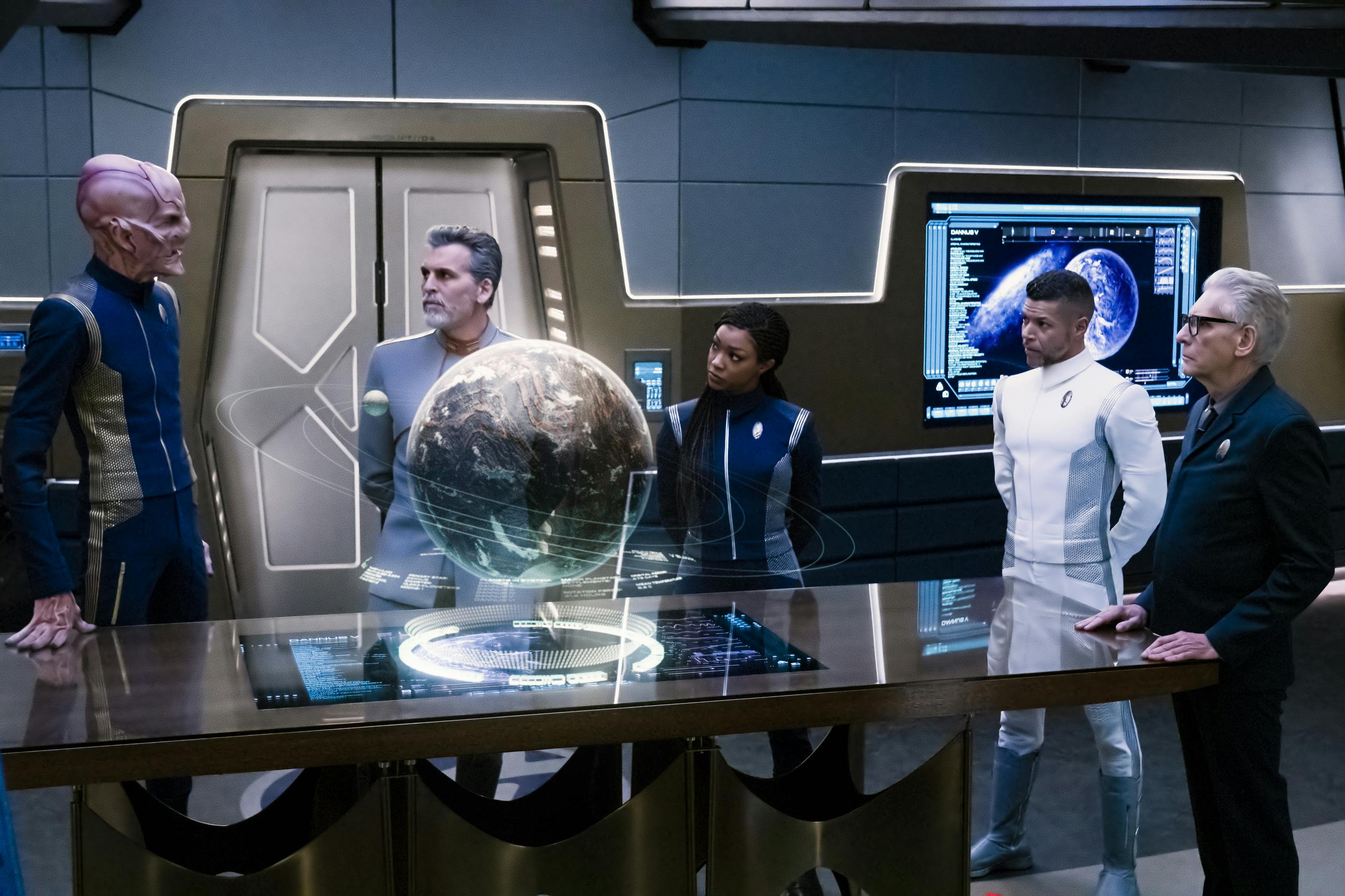 In the Ready Room, surrounding a projection above a large table, Admiral Vance, Burnham, Culber, and Kovich all look towards Saru in 'Terra Firma, Part 1'