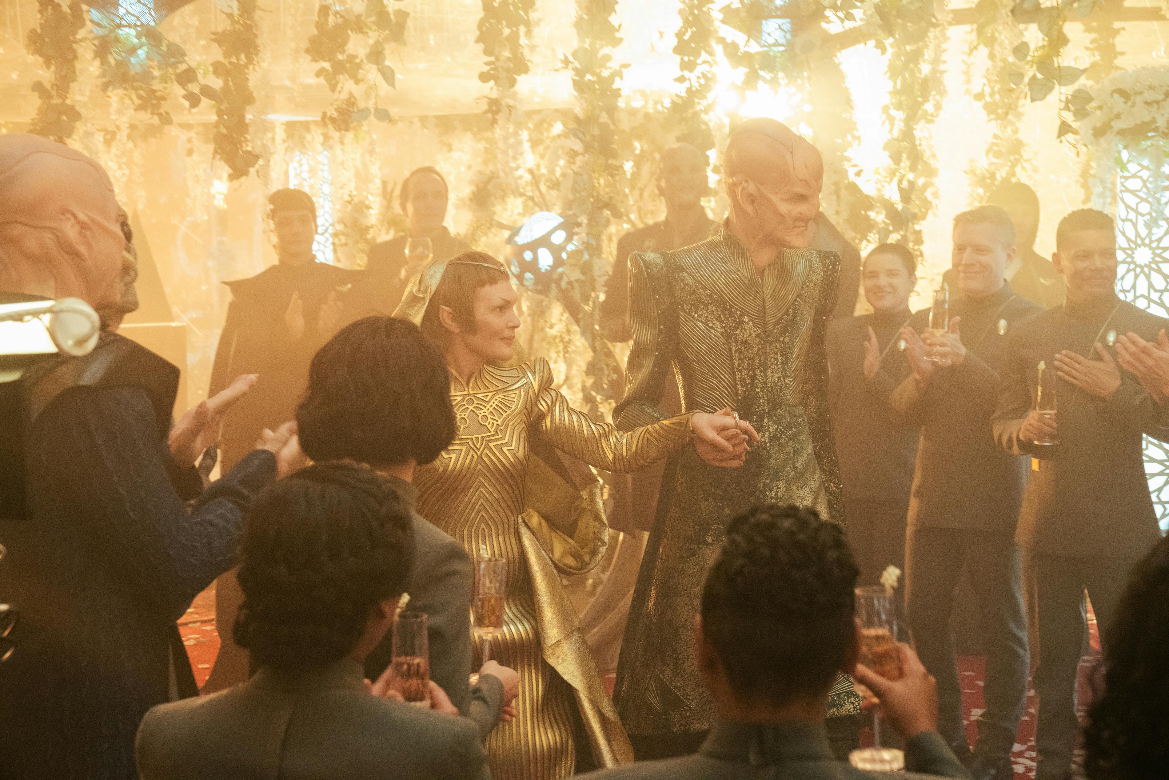 Behind-the-scenes of Saru and T'Rina's wedding as he leads her into the room with all the guests surrounding them raising glasses and clapping in 'Life, Itself'