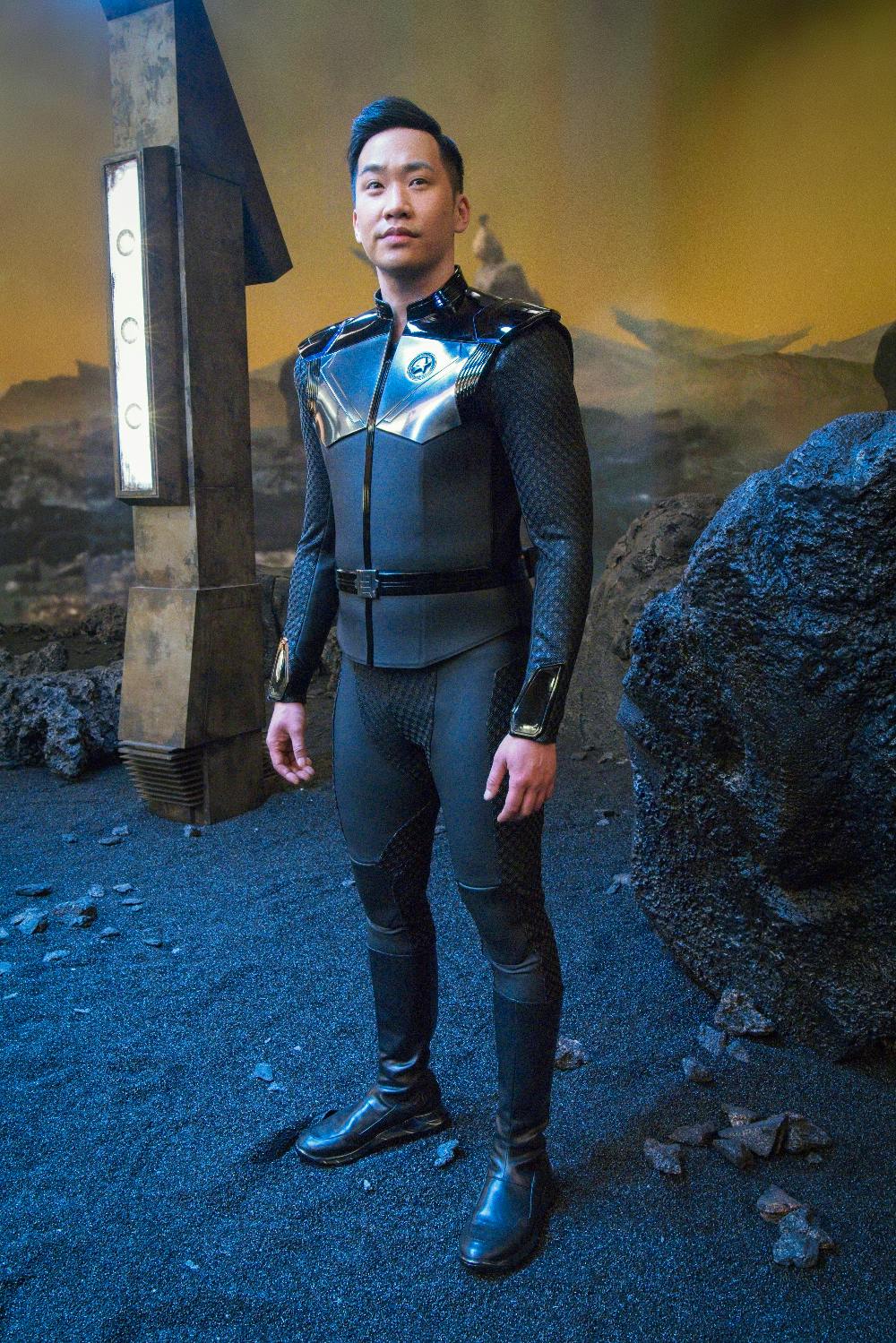 Patrick Kwok-Choon as Gen Rhys stands on the surface of a planet behind-the-scenes on set of 'The Examples'