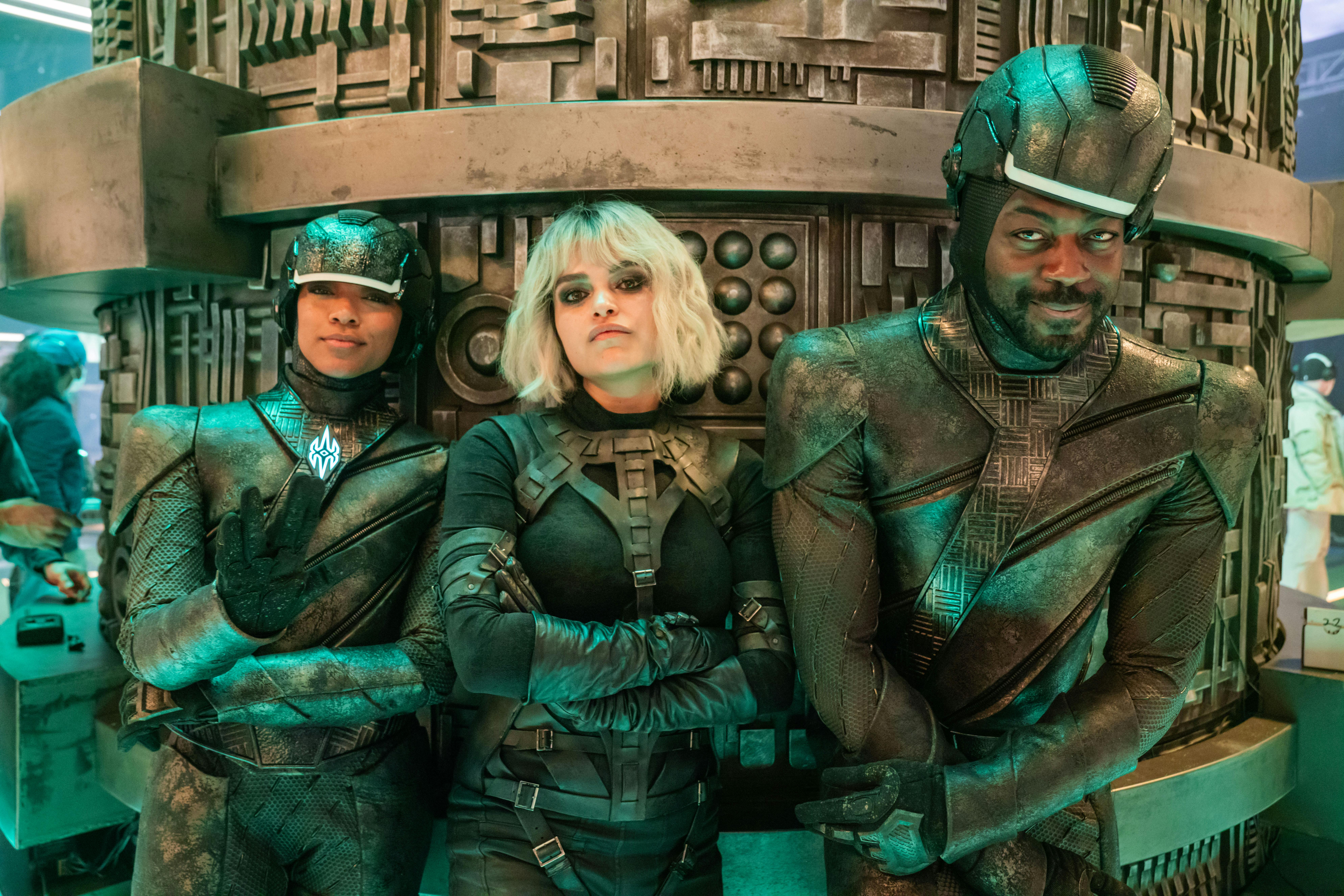 Behind-the-scenes of 'Lagrange Point' - Sonequa Martin-Green and David Ajala in Breen soldier uniform and Eve Harlow all lean against a structure on the set of the Breen dreadnaught bridge