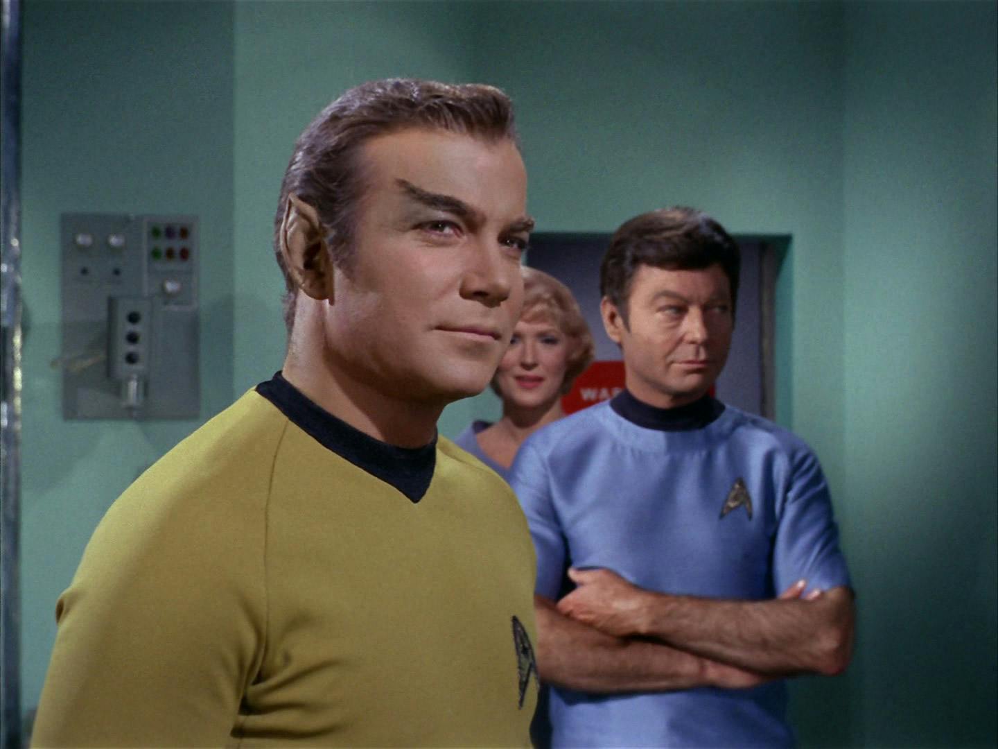 Kirk poses as a Romulan officer with McCoy's assistance as Nurse Chapel looks on in 'The Enterprise Incident'