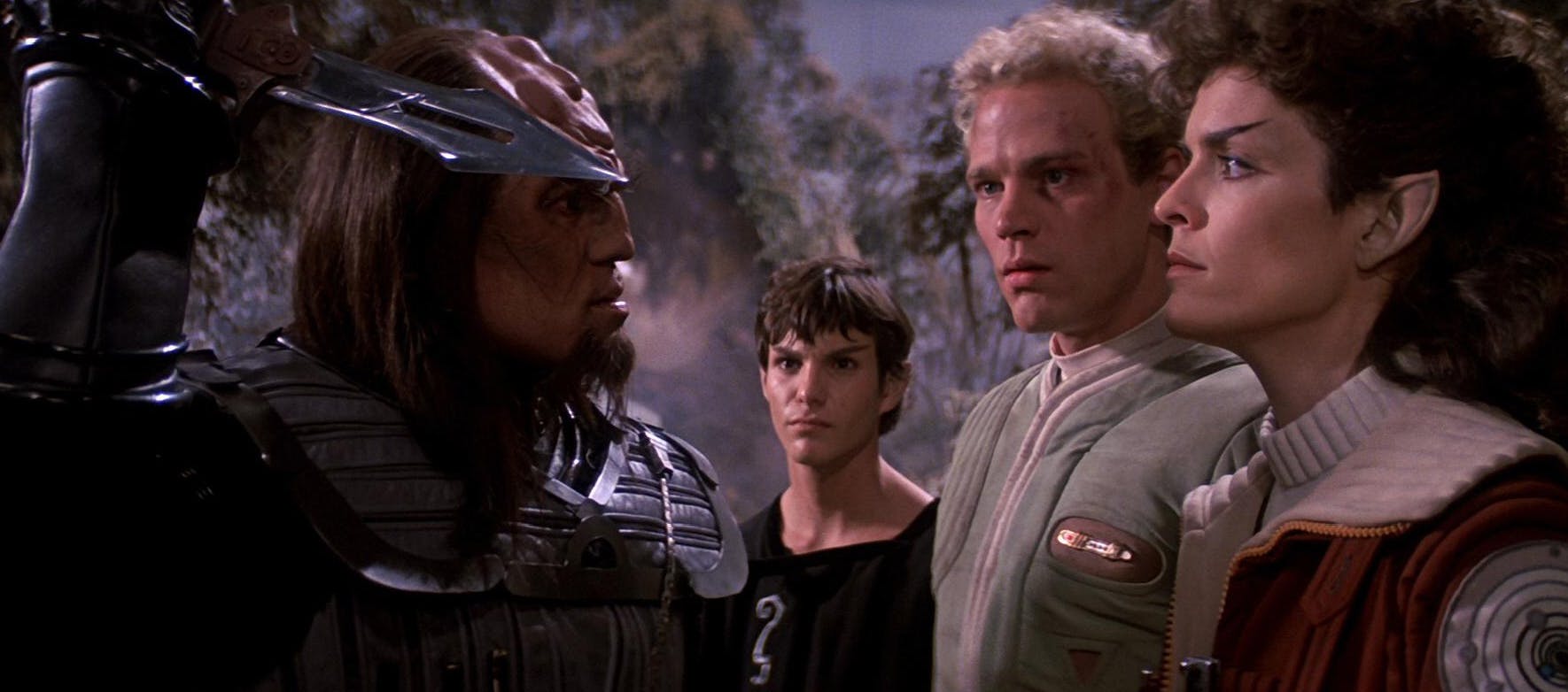A Klingon lifts his dagger above him facing Saavik who reflects his intense gaze as David Marcus and a young Spock look at their foe in Star Trek III: The Search for Spock