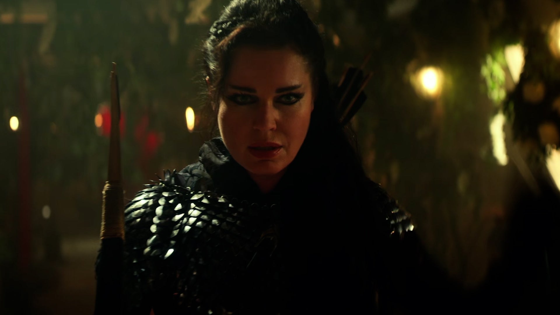 Number One (Rebecca Romijn), wearing armor and holding a bow and arrow, stands in the Enterprise's corridor, which is overgrown with foliage.