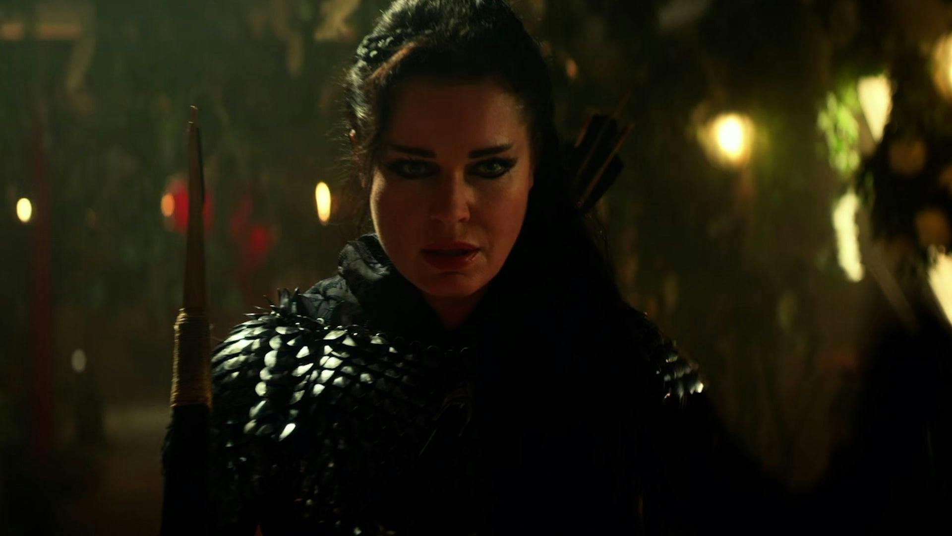 Number One (Rebecca Romijn), wearing armor and holding a bow and arrow, stands in the Enterprise's corridor, which is overgrown with foliage.