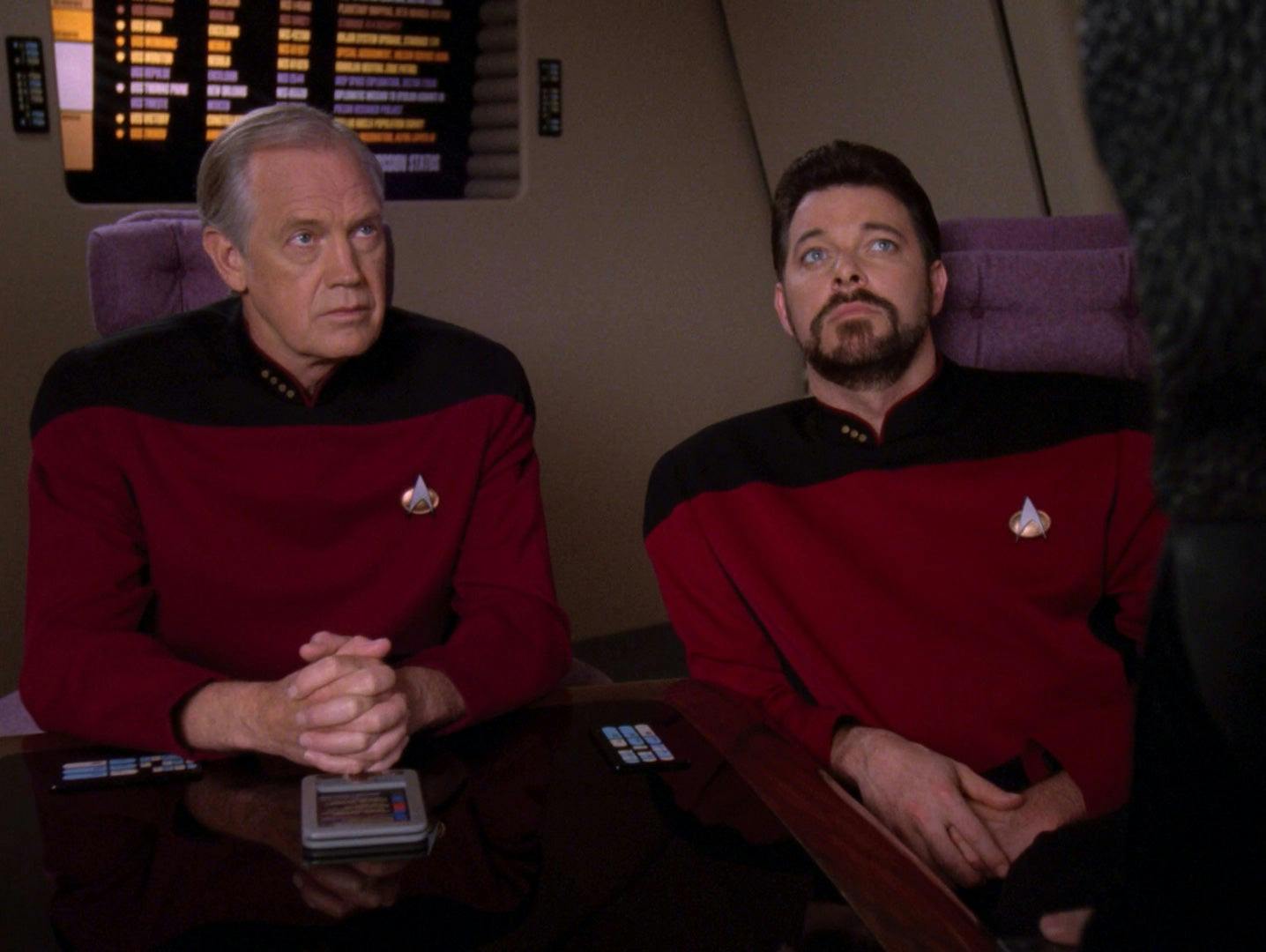In the Observation Lounge, Jellico and Riker sit at the conference table looking to someone off-camera in Star Trek: The Next Generation