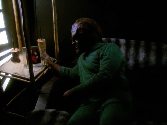 Worf in bed leans over to the nightstand to look at his framed wedding photo with Jadzia in 'Image in the Sand'
