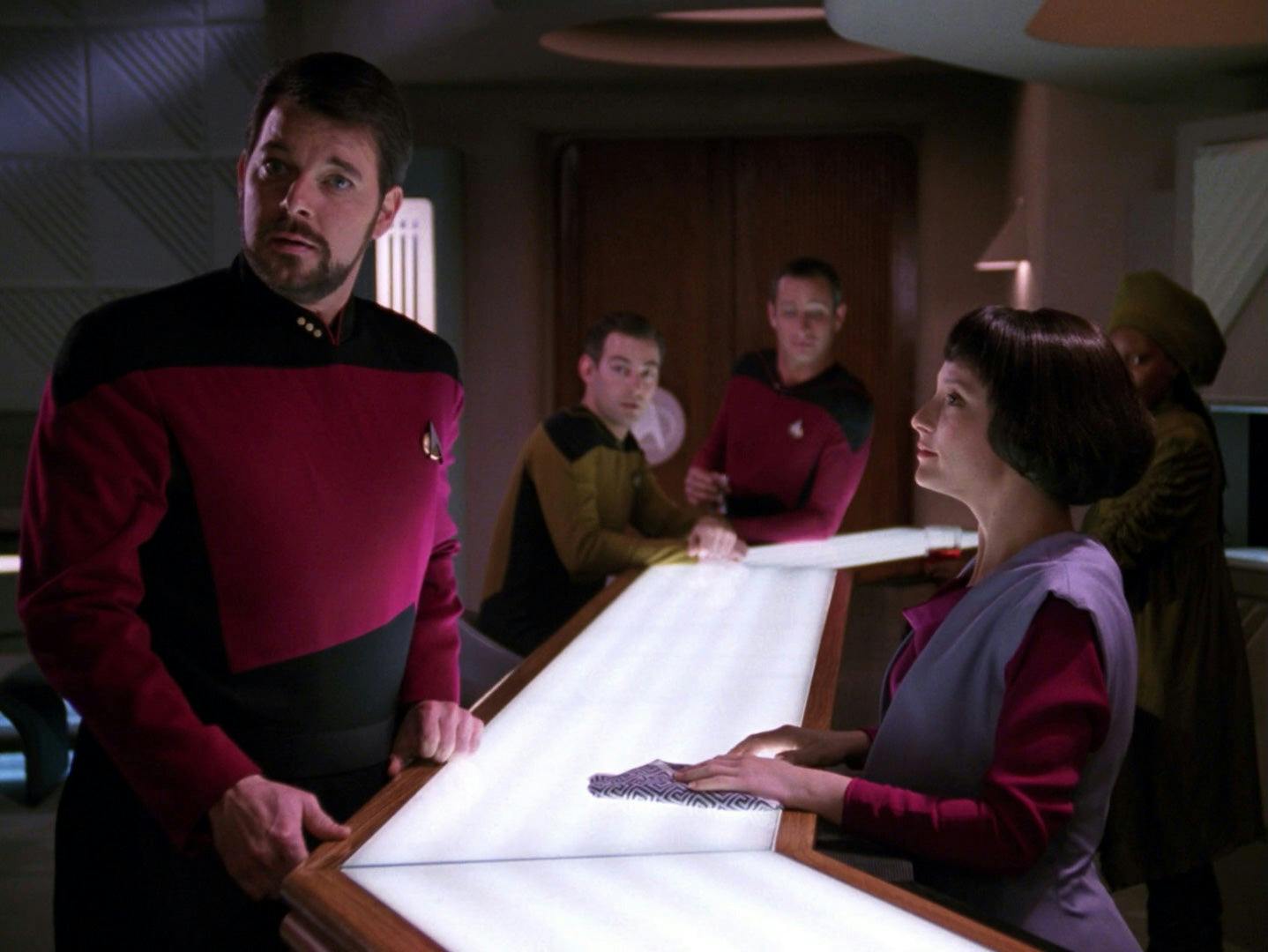 Riker turns to the door of 10 Forward as Lal looks at him from across the bar table in 'The Offspring'