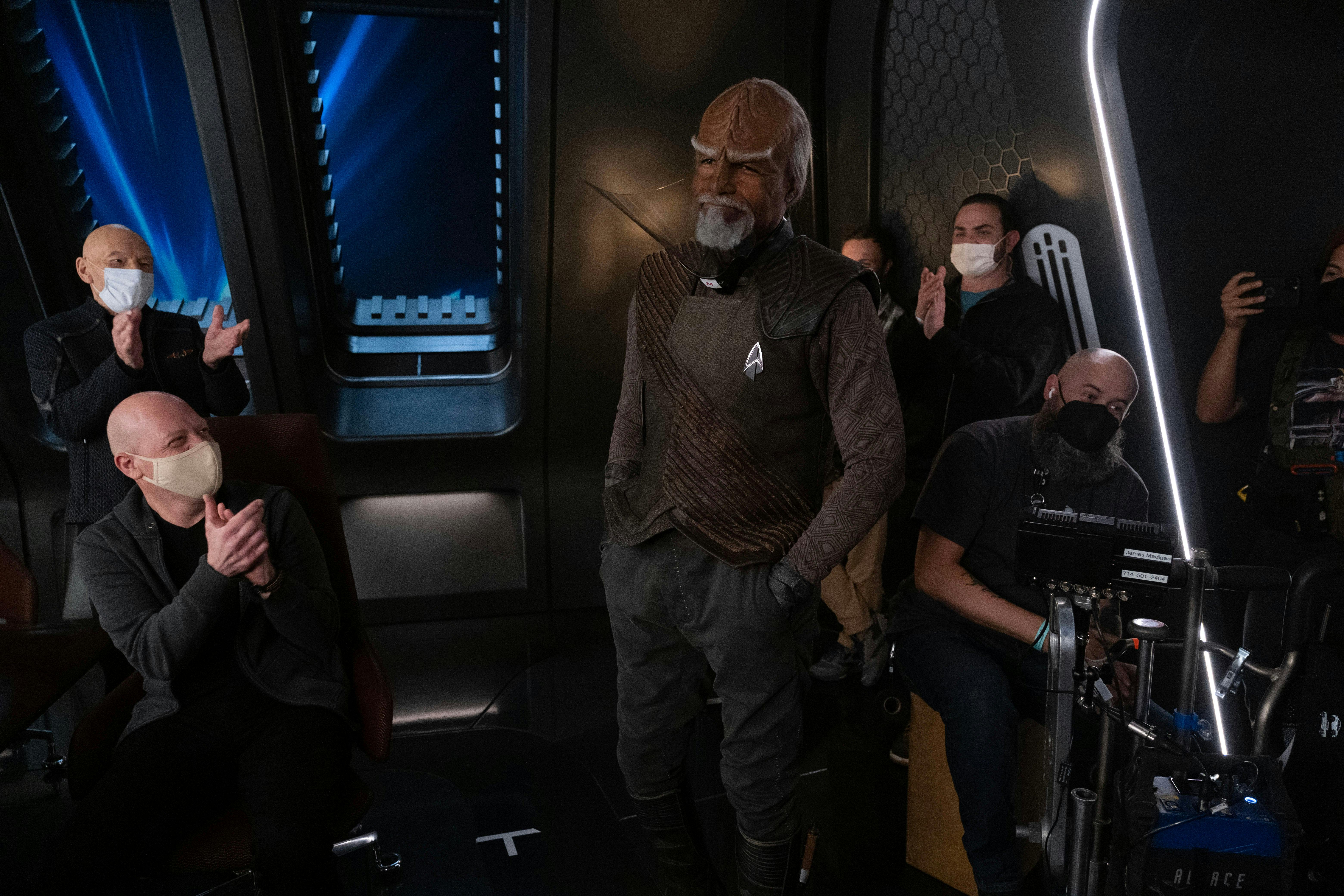 Star Trek: Picard BTS still - crew smile and clap as they all face Michael Dorn in the Observation Lounge set