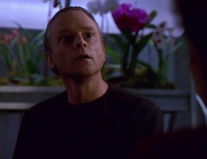 Suder looks up while sitting in front of his plants on Star Trek: Voyager