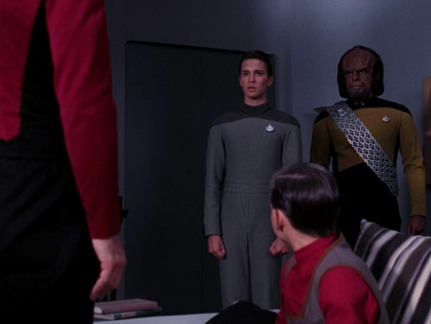 In the Asters' quarters, Worf and Wesley approach a standing Jean-Luc Picard and seated Jeremy Aster as young Crusher confronts the captain about his long-held resentment in 'The Bonding'