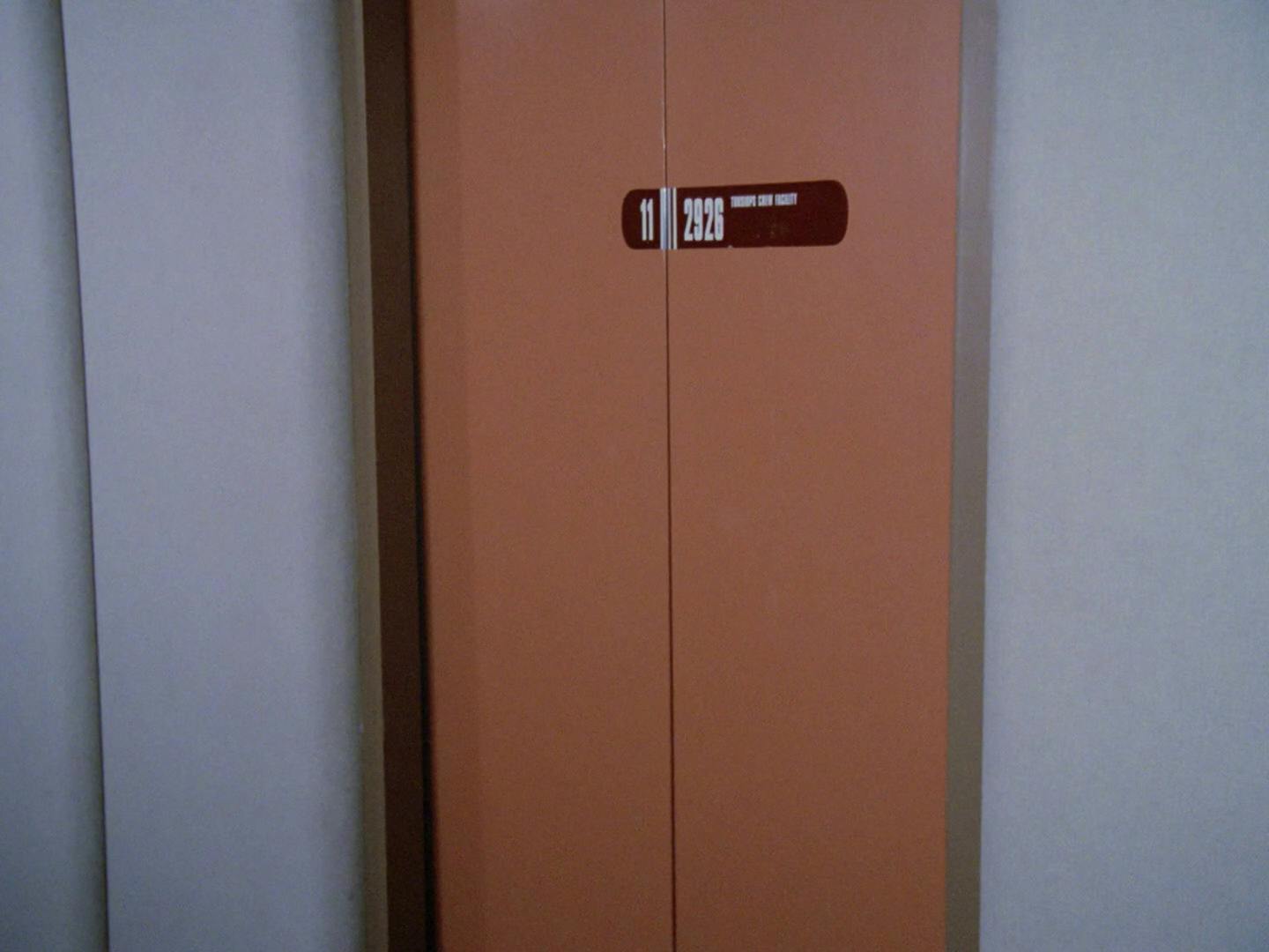 Close-up of the turbolift doors to a holodeck corridor that read '11 2926 Tursiops Crew Facility' in 'We'll Always Have Paris'
