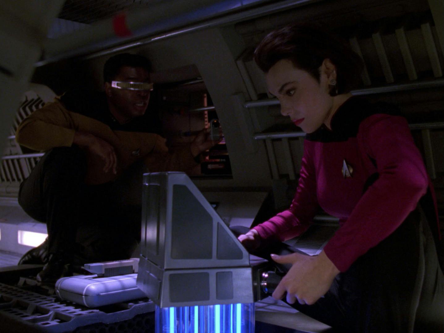 Crouched in a Jefferies tube, Geordi La Forge and Ro Laren prepare to spring a trap with a plasma inverter in 'Power Play'