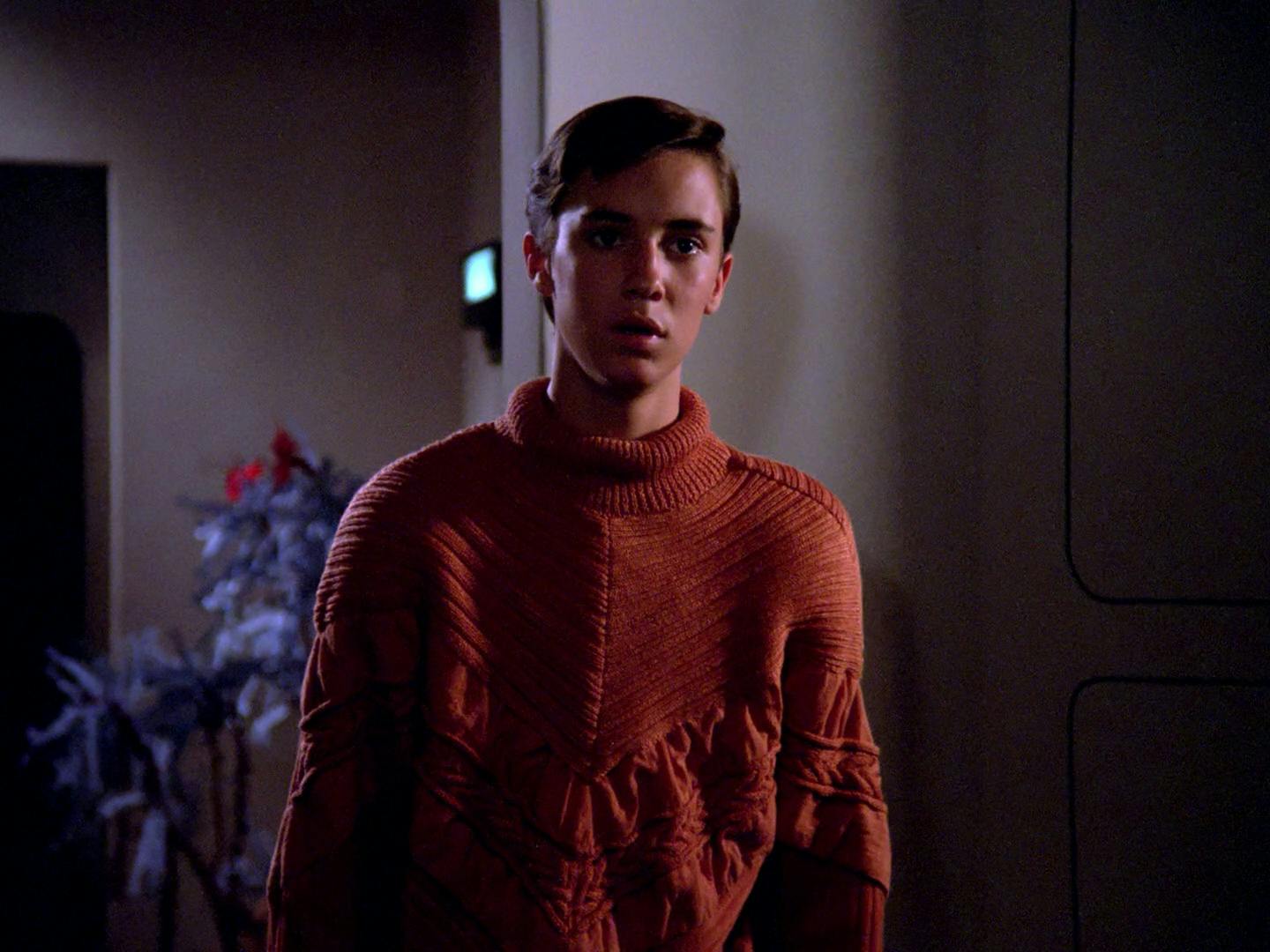 Wesley Crusher in his orange braided sweater stands in the dimly lit quarters in 'Where No One Has Gone Before'