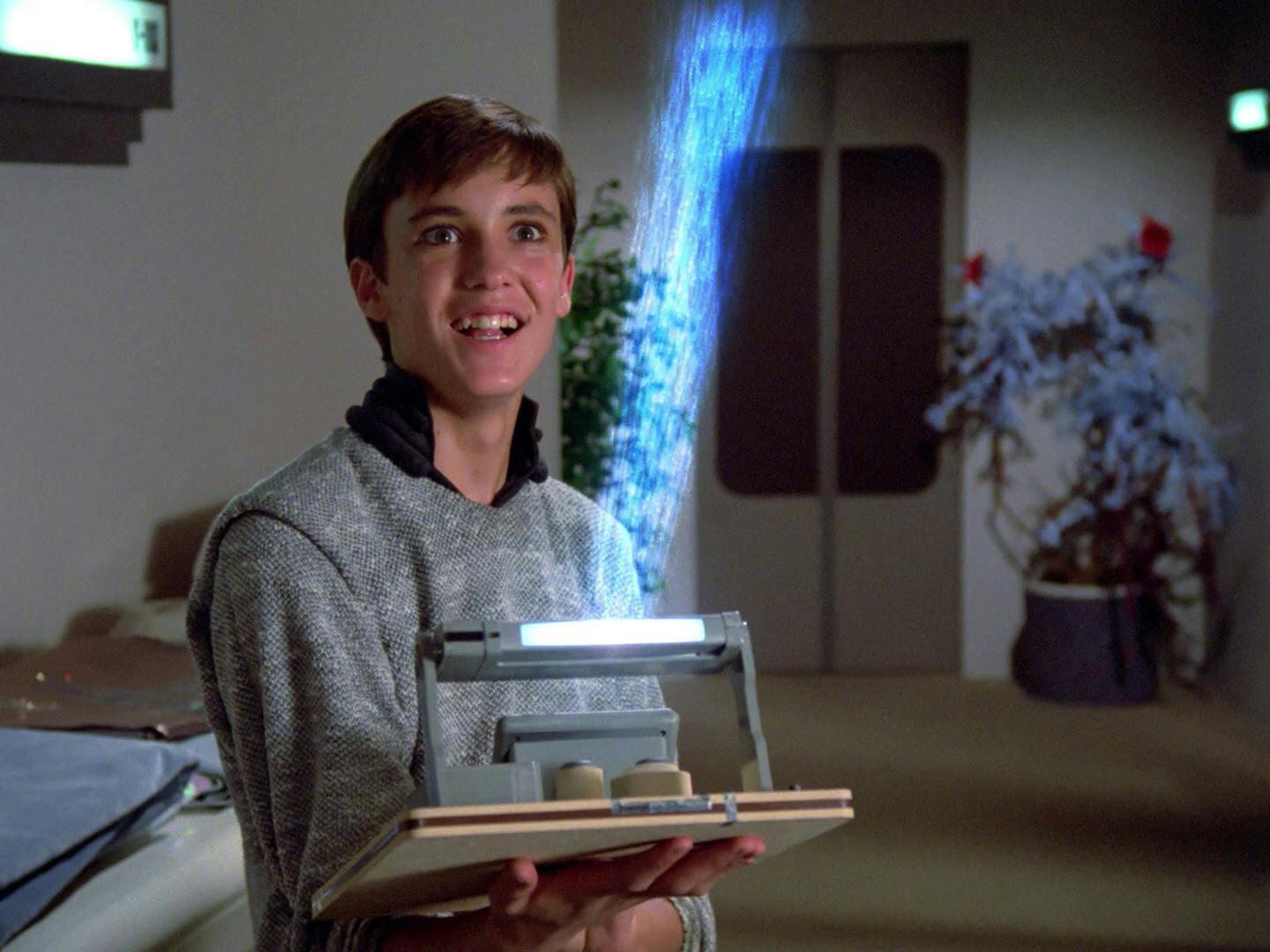 Wesley Crusher holds his experiment as he raises it in his arm in 'The Naked Now'