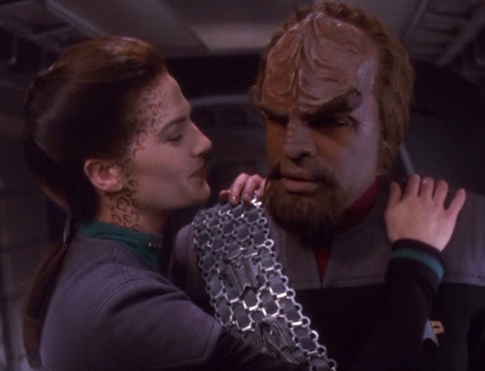 In a corridor, Jadzia Dax lovingly gazes at Worf with her hands around his shoulders following an intimate kiss in 'Tears of the Prophets'