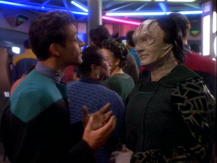 While standing in line for the replimat, Julian Bashir and Garak are face-to-face engaged in a lively discussion about Cardassian literature in 'The Wire'