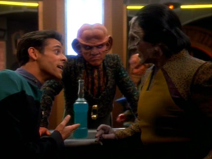 Quark leans in from across the bar to listen in on Julian Bashir and Garak's conversation in 'The Wire'