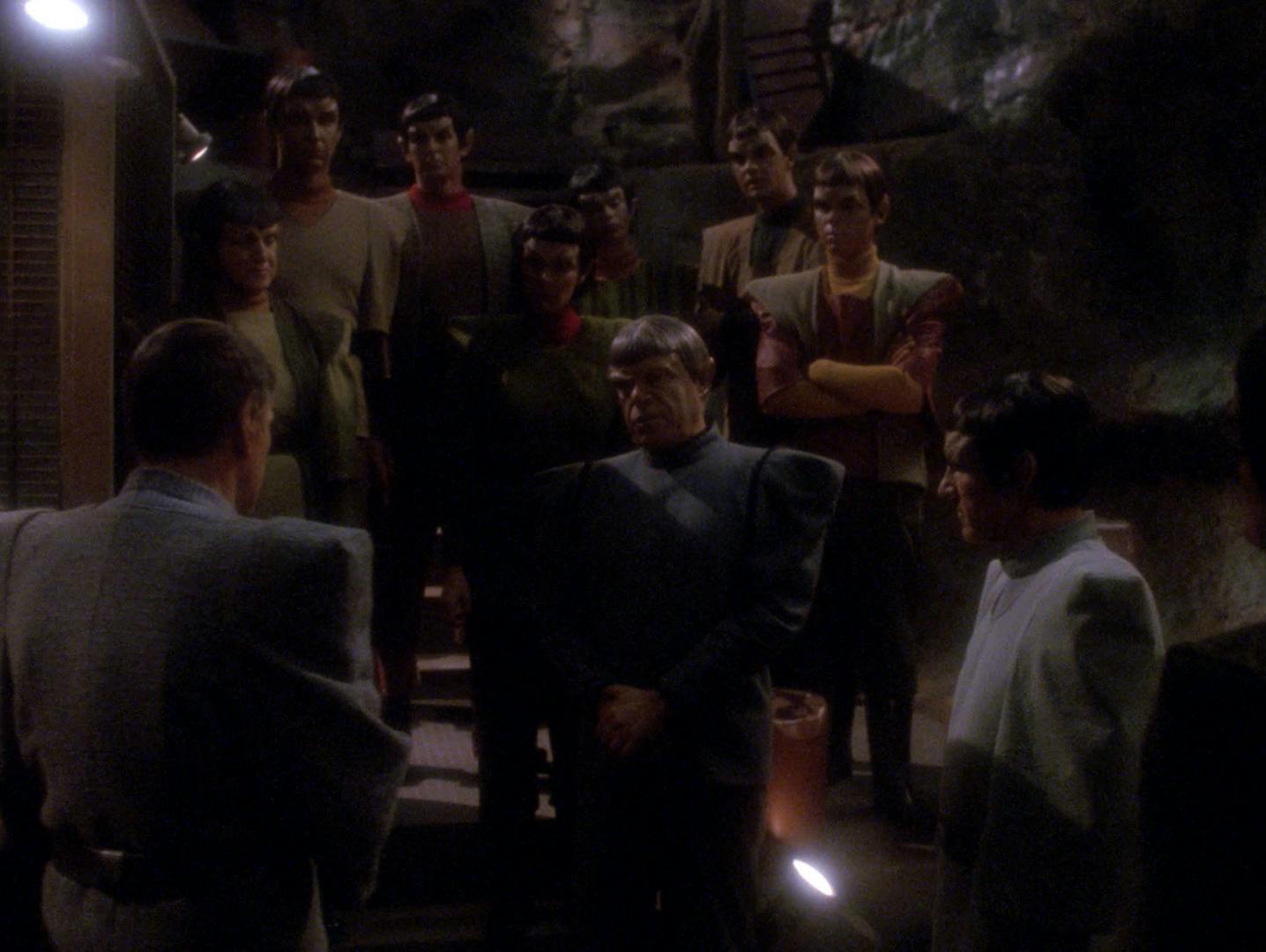 Underground on Romulus, a group of Romulan dissidents stand on steps looking at Ambassador Spock and Picard disguised as a Romulan in 'Unification, Part II'