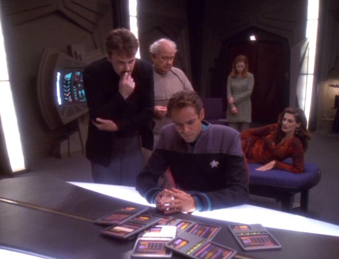 Dr. Julian Bashir looks over a handful of PADDs while surrounded by a group of eccentric fellow genetically-engineered Humans in 'Statistical Probabilities' 