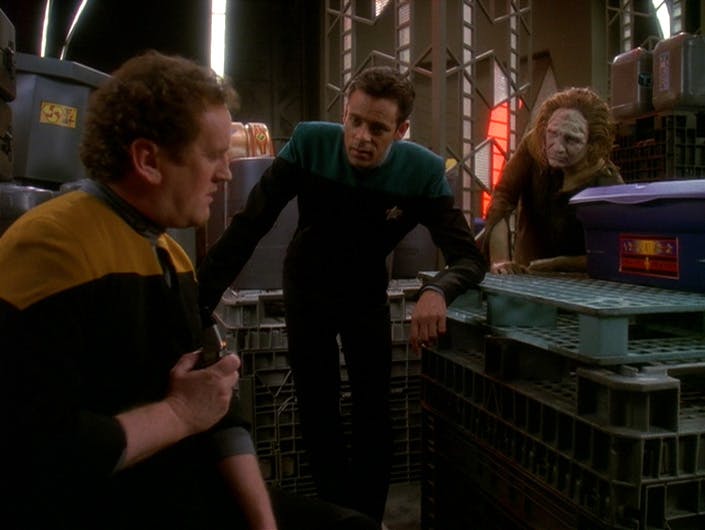 Miles O'Brien opens up to Julian Bashir as he crouches over some crates in 'Hard Time'