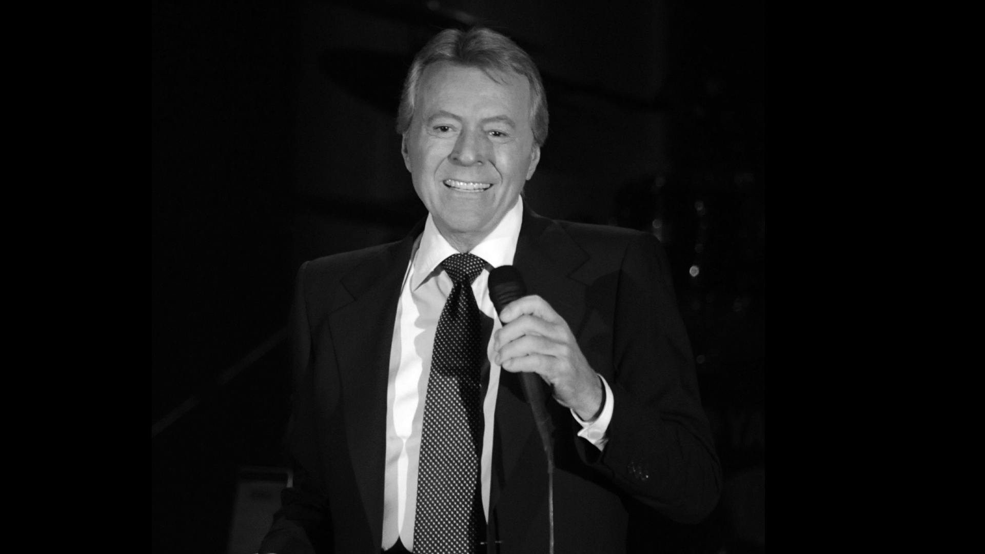 Black and white photo of James Darren performing on stage with a mic in hand