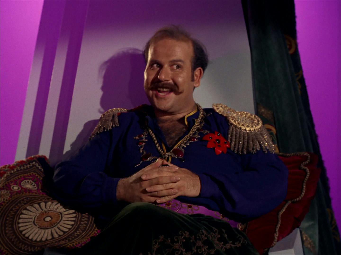 Harry Mudd leans back in his throne grinning as he clasps his hands in 'I, Mudd'