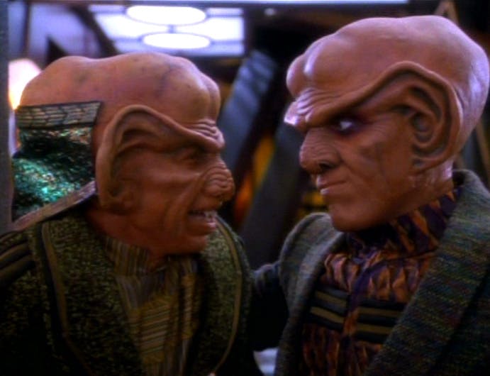 Close-up the side profiles of brothers Rom as he's stared down by Quark in his bar in 'The Nagus'