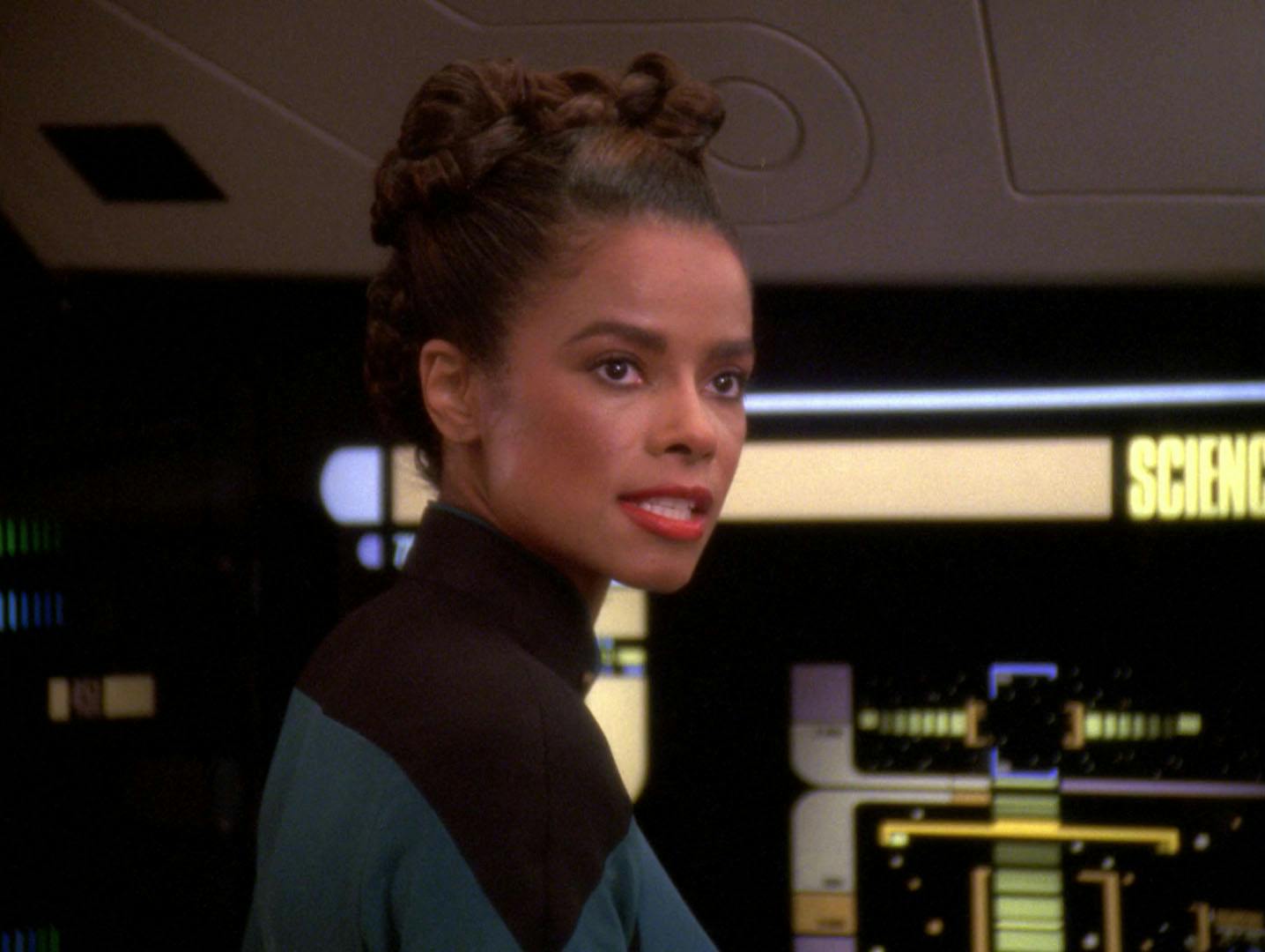 Ensign Taitt looks over her shoulder as she stands at the science station in 'Descent, Part II'