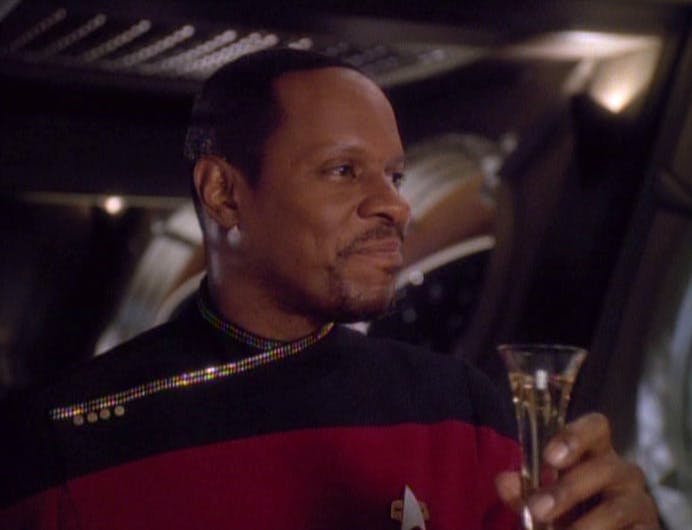 Benjamin Sisko raises a glass as he toasts his promotion to captain in 'The Adversary'