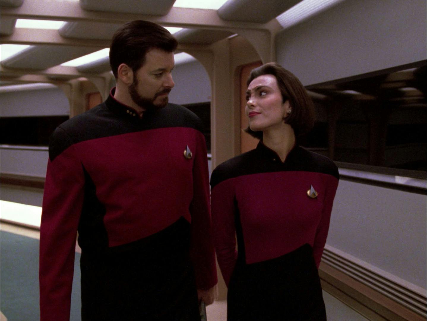 William Riker and Ensign Ro walk side by side in a corridor as they gaze upon each other in 'Conundrum'