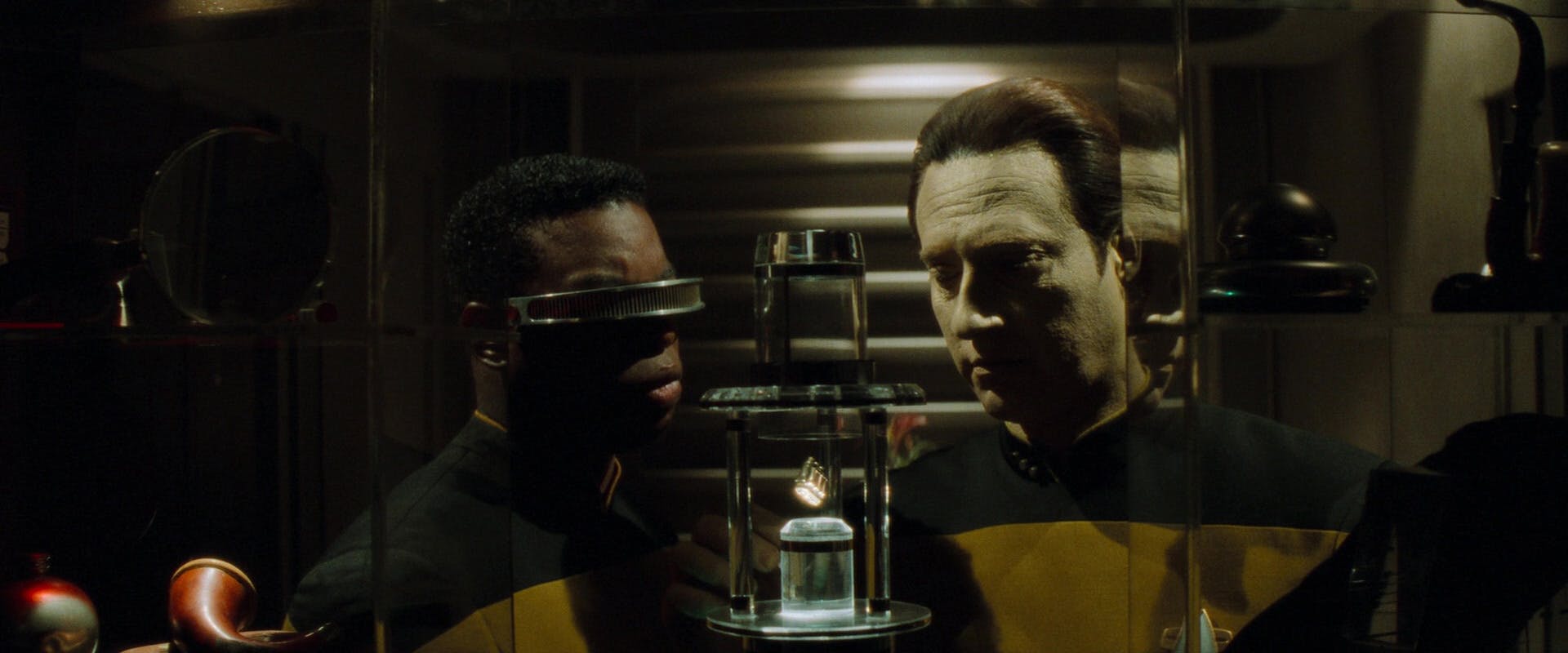 Geordi La Forge and Data look at an emotion chip within a glass case in 'Star Trek Generations'