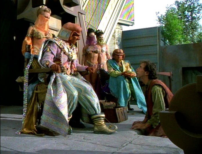 Two Ferengi known as the Holy Sages take advantage of a primitive planet while surrounded by their harem in 'False Profits'