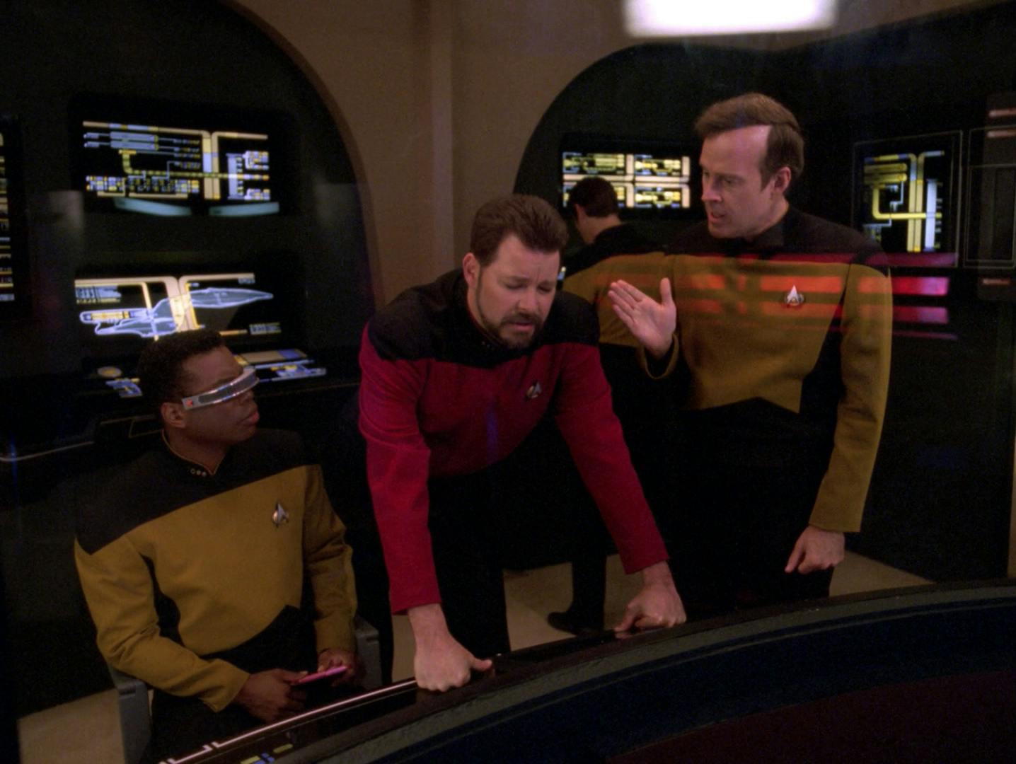 In Engineering, Riker struggles to focus and leans over the console in between La Forge and Barclay in 'Genesis'