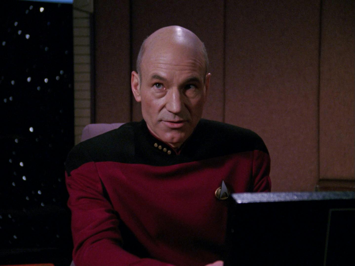 Seated in his Ready Room, Picard looks up as he addresses Riker and La Forge in 'Hollow Pursuits'